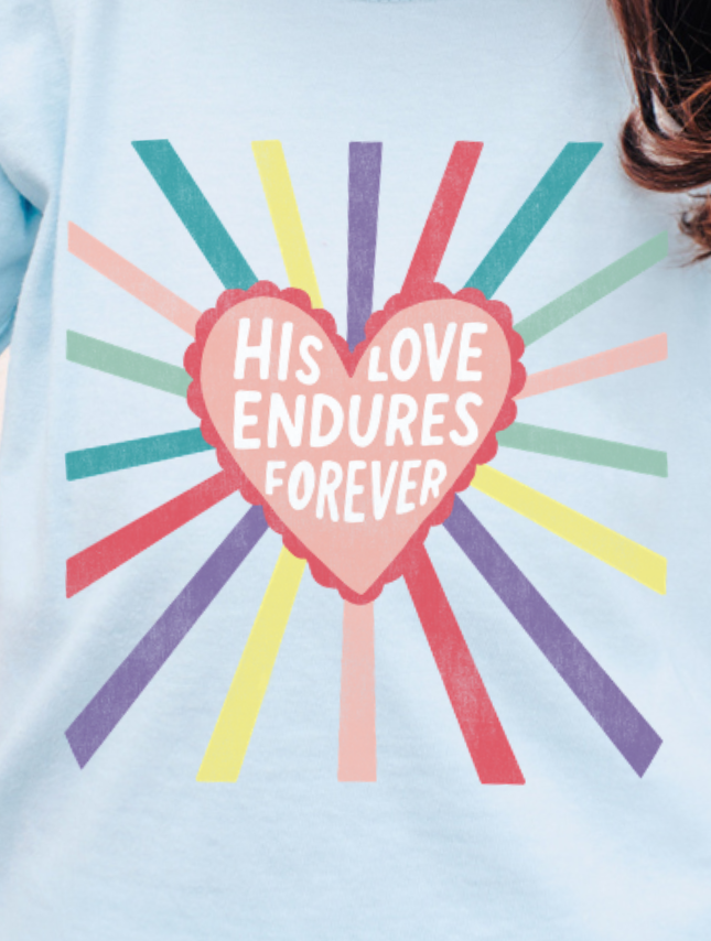 Light blue youth tee featuring a heart graphic with the text "His Love Endures Forever" and colorful rays radiating outward.