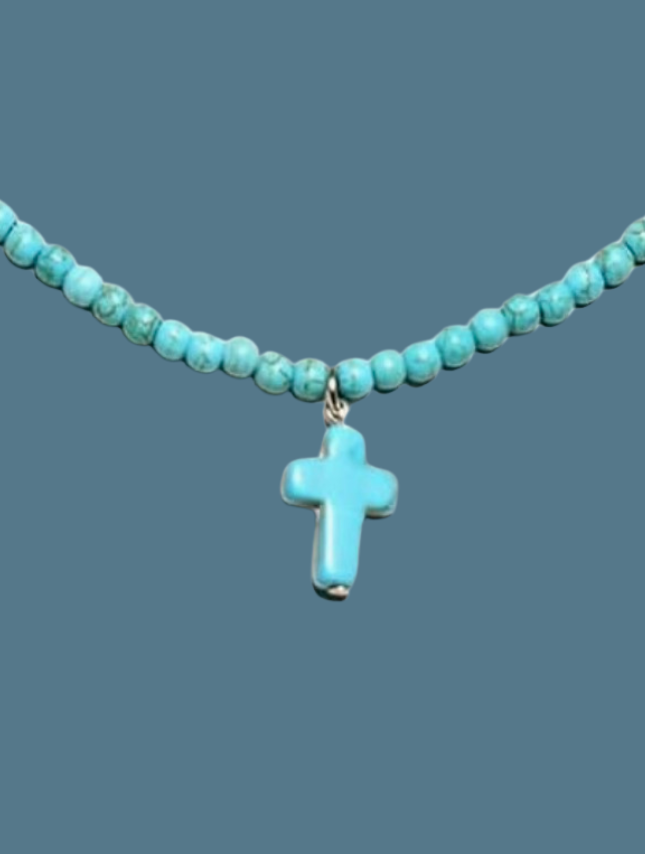 Turquoise beaded cross necklace featuring a small cross pendant on a strand of turquoise beads.