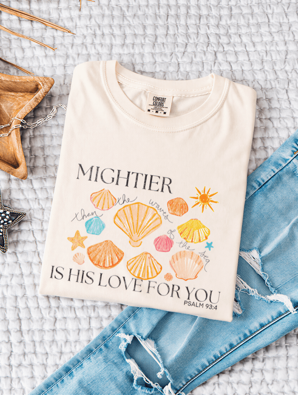 flat lay of Mightier Is His Love Tee